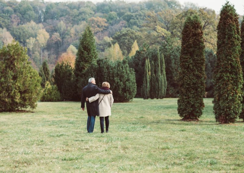 Man and woman with arms around each other walking in a meadow
